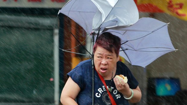 A woman struggles with her umbrella in Taipei as Typhoon Megi hits.