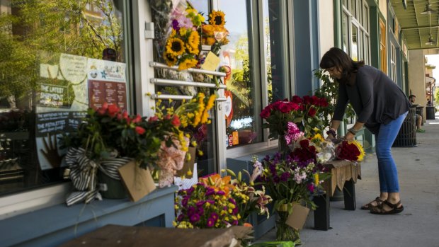 A woman leaves a bouquet of flowers at a makeshift memorial for store co-owner Jillian Johnson at Red Arrow Workshop in River Ranch in Lafayette on Friday.