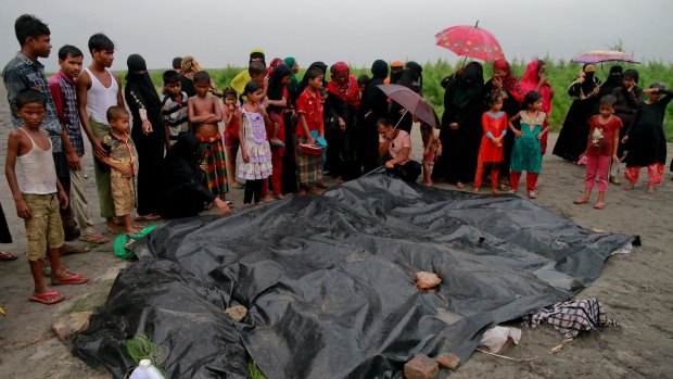 Bangladeshi villagers gather around the covered bodies of Rohingya women and children who died after their boat capsized.