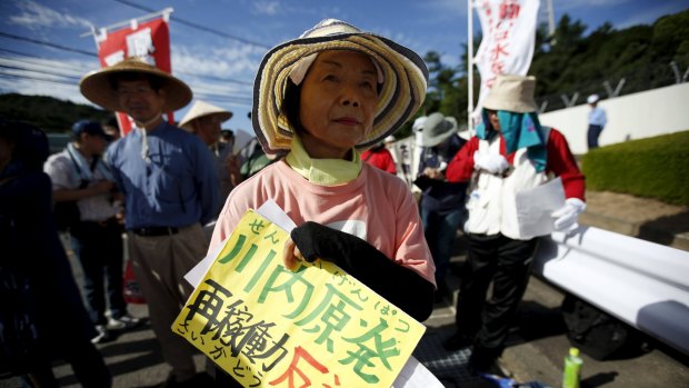 A protester attends a rally against the restarting of the plant at an entrance gate of Kyushu Electric Power's Sendai nuclear power station.