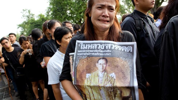 A Thai woman weeps as she holds on to a portrait of King Bhumibol Adulyadej.
