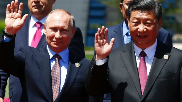 Chinese President Xi Jinping, right, and Russian President Vladimir Putin wave at the Belt and Road Forum on Yanqi Lake just outside Beijing on Monday.