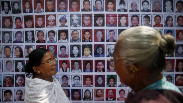 Nepalese women stand near photographs of victims of the earthquakes.