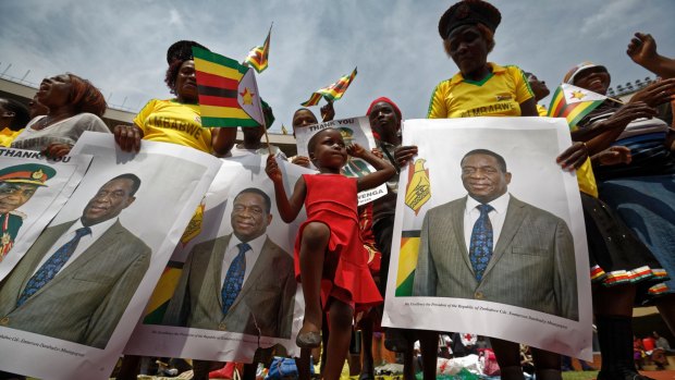A young girl marches in position as she mimics the military parade, accompanied by supporters holding posters of President Emmerson Mnangagwa, at his inauguration.