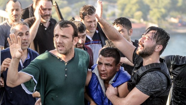 People apprehend a Turkish soldier, centre in blue, who participated in the attempted coup, on Istanbul's Bosporus Bridge.
