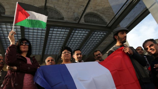 Palestinians hold French and Palestinian flags ahead on the vote.