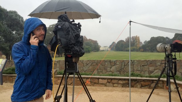 A wet and cold Nine Network cameraman wishes his mother Happy Mother's day while staking out Government House.