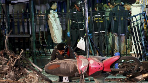 Experts investigate the remains of destroyed motorcycles at the Erawan shrine.