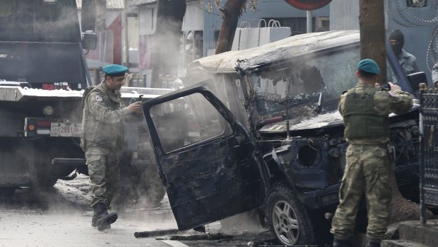 Turkish soldiers take pictures of a vehicle at the site of a suicide attack in Kabul.