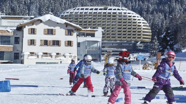 Children are skiing near the hotel Intercontinental, background, where most of the head of States stay during the World Economic Forum in Davos, Switzerland.
