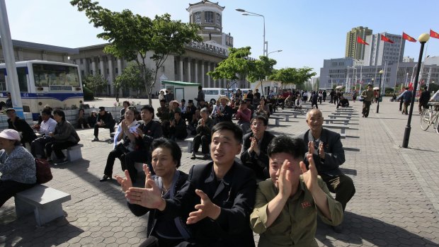 Devotees: North Koreans clap as they listen to Kim Jong-un speak at the party congress during a television broadcast on a screen near the Pyongyang train station on Sunday.
