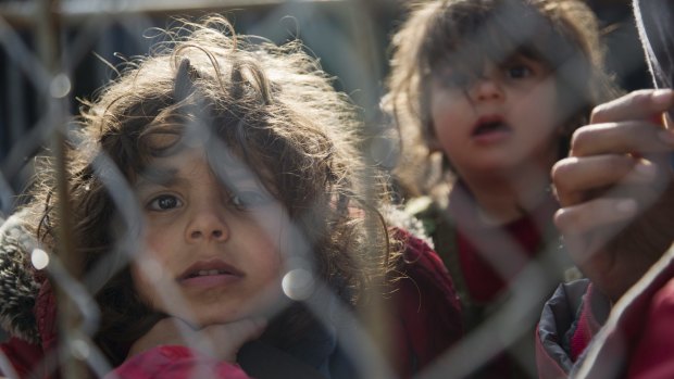 Migrant children wait by the fence on the Greek side of the border to enter Macedonia in March.