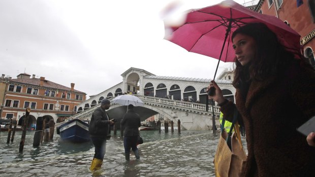 People walk near the Rialto bridge on the occasion of a high tide.