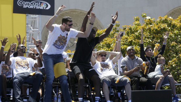 Front-court partners: Golden State Warriors centre Andrew Bogut and forward Draymond Green stand up as teammates react during a rally for winning the NBA championship.