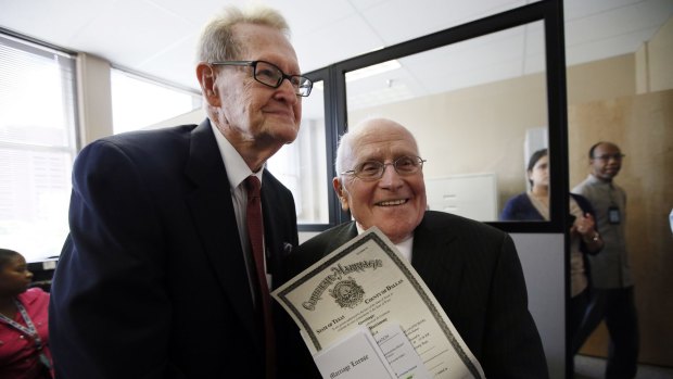 Jack Evans, 84, left, and George Harris, 82, right, show their marriage licence after being the first couple to receive it from the Dallas County Clerk.