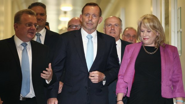 Flanked by MPs, Prime Minister Tony Abbott leaves the party room meeting on Monday.