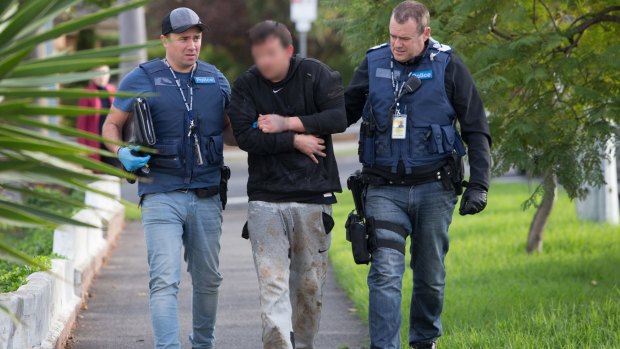 Police lead a man arrested in St Albans to a house in Essendon where further searches were carried out in May. 