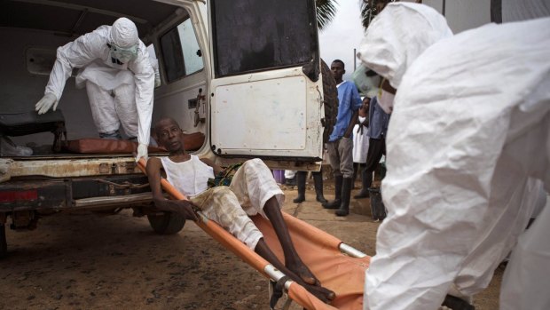 Saving lives: Healthcare workers assist a suspected Ebola sufferer in Sierra Leone.