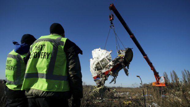 Investigators watch as a piece of wreckage from the Malaysia Airlines flight MH17 is recovered near the village of Grabovo in the Donetsk region of eastern Ukraine.