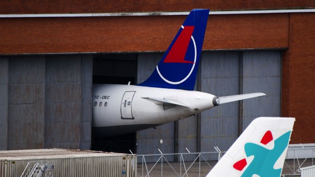 The tailfin of a grounded Airbus SE A321 passenger aircraft, operated by Onur Air, protrudes from a hangar at Chateauroux airport.