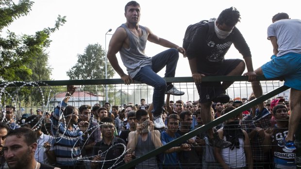 Refugees climb a border fence that separates Serbia from Hungary before violence broke out on Wednesday.