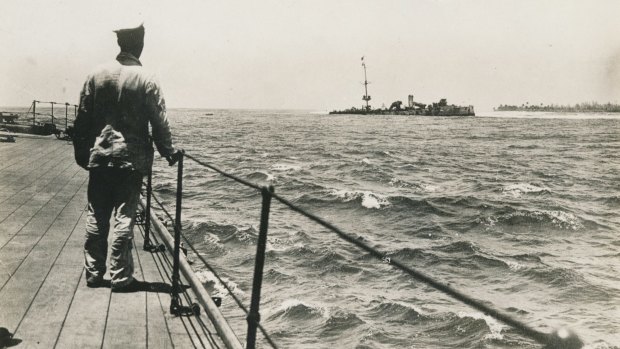 An unidentified seaman on the quarter deck of HMAS Sydney looks at the wrecked German cruiser Emden