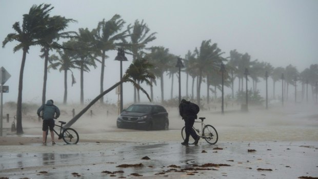 Two men walk their bicycles along a flooded street on the waterfront of Fort Lauderdale, Florida.