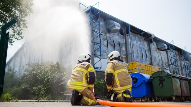 Firefighters try to extinguish flames at refugee accommodation on the grounds of the exhibition centre in Dusseldorf
