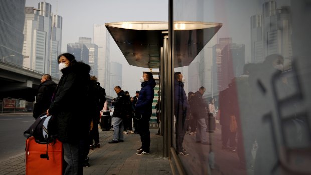 Commuters wearing protection masks wait for buses at a bus stand on a polluted day in Beijing last year. 