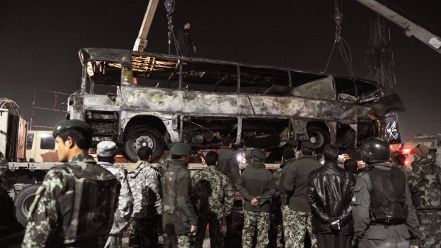 Spate of attacks: Afghan soldiers watch as the wreckage of an army bus is taken away from the scene of the attack.