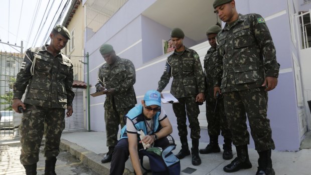 Surrounded by soldiers, a government health agent uses larvicide to kill mosquitos that spread the Zika virus, in the Tijuca neighbourhood of Rio de Janeiro, Brazil, on Monday.