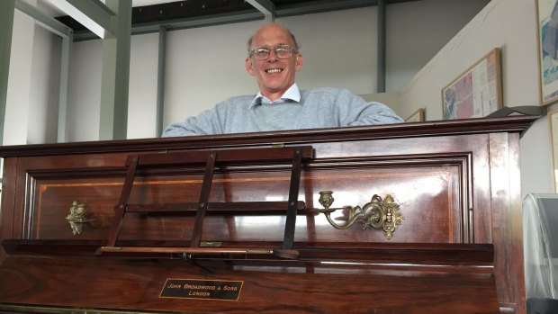 Tuner Martin Backhouse with the piano where he found a stash of gold.