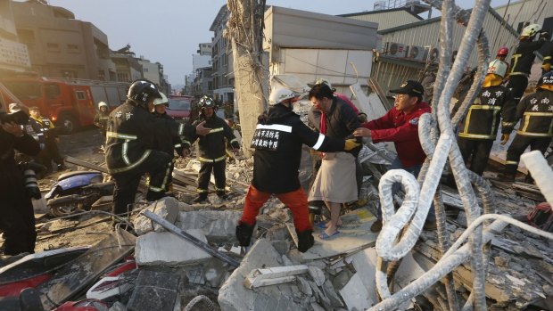 Rescue workers guide a man from the rubble of a toppled building after an earthquake in Tainan on Saturday. 