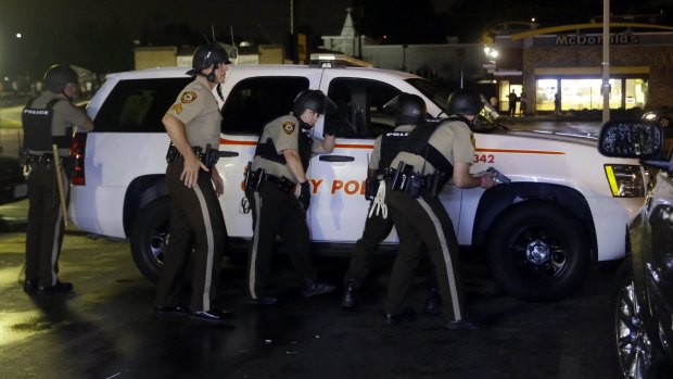Police officers take cover at a protest in Ferguson.