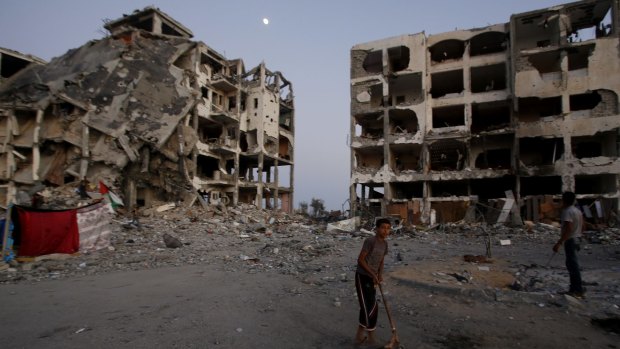 A Palestinian plays in a courtyard near destroyed buildings at a residential neighbourhood in Beit Lahiya, northern Gaza Strip, in August 2014. 