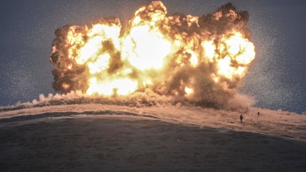 This October 23 photo shows militants of Islamic State as they stand next to the explosion of an air strike on Tilsehir Hill near the Turkish border, at Yumurtalik village.  