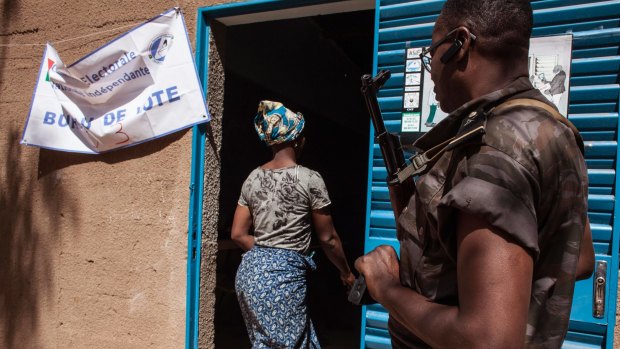 A Burkina Faso soldier provides security outside a polling station as a woman enters to cast her ballot in Ouagadougou on Sunday.