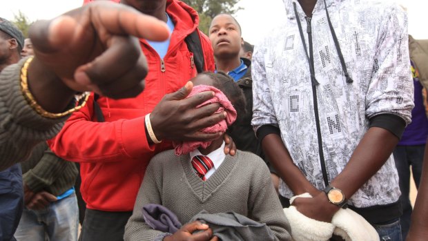 A father covers his daughter's face with a wet towel after she was teargassed by armed Zimbabwean police.