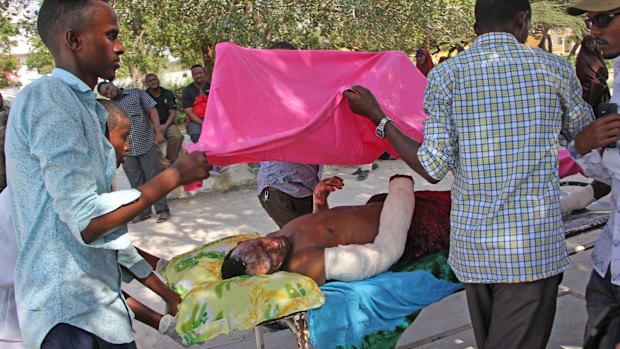 Somalis help a civilian wounded in Saturday's blast.