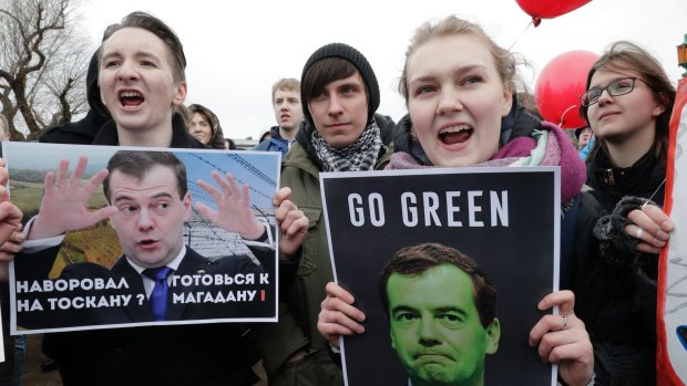 Protesters hold posters depicting Russian Prime Minister Dmitry Medvedev who is accused of corruption.