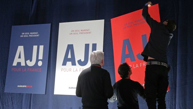 Election officials readjust a campaign poster prior to the speech of French presidential contender Alain Juppe after the first round if the primary in Paris on Sunday.