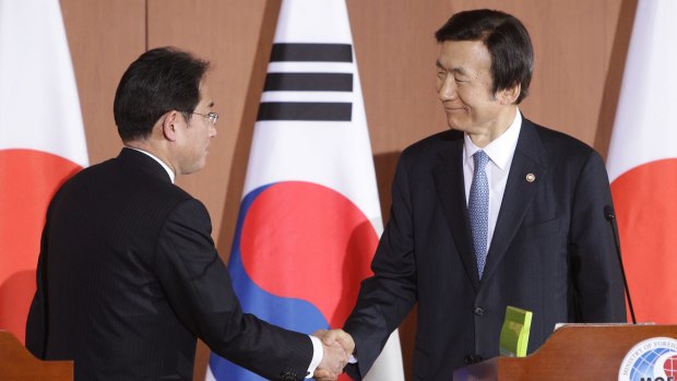 South Korean Foreign Minister Yun Byung-Se (right) shakes hands with Japanese Foreign Minister Fumio Kishida after their joint news conference.