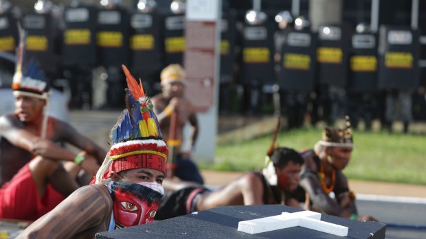 Indigenous protesters from various ethnic groups take cover during clashes with riot police in Brasilia.