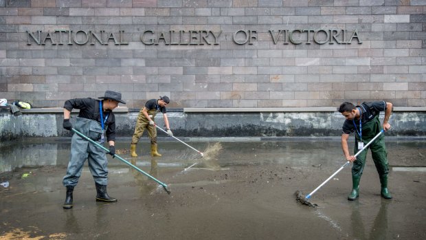 Cleaners work on the moat at the NGV. The collected coins are recorded as NGV donations and will go towards the acquisition of art.