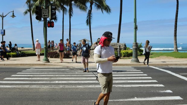 A new Honolulu ordinance allows police officers to issue tickets to pedestrians caught looking at a phone or electronic device while crossing a city street.