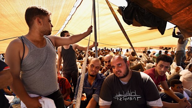 Rafaa, 34, (front, third from right) from Benghazi in Libya sits on the upper deck of the MY Phoenix heading for Italy with more than 400 others rescued at sea. 