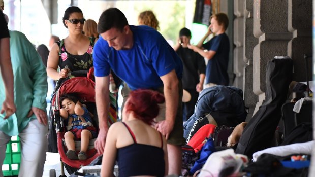 A mother and child pass the homeless camp along Flinders Street. 