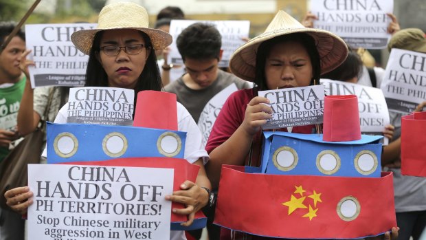 Filipino student activists hold mock Chinese ships to protest recent island-building in the South China Sea.
