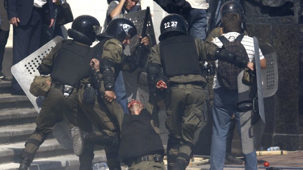 Police officers carry their injured colleague after a grenade exploded during a clash outside the Parliament in Kiev.