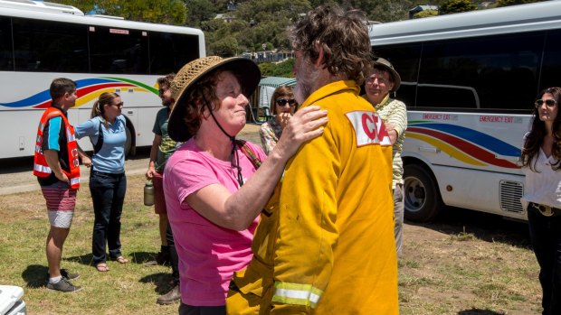 Wye River CFA Captain Roy Moriarty gets a hug from a home owner/resident after she was bussed in to the Wye River fire ground. 